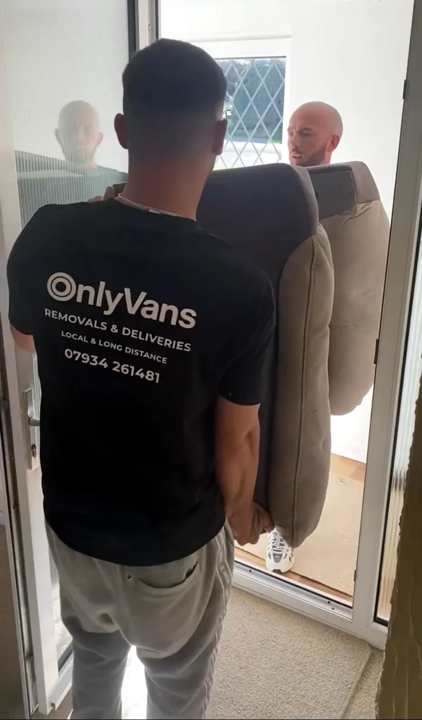 OnlyVans team carefully carrying a sofa through a doorway